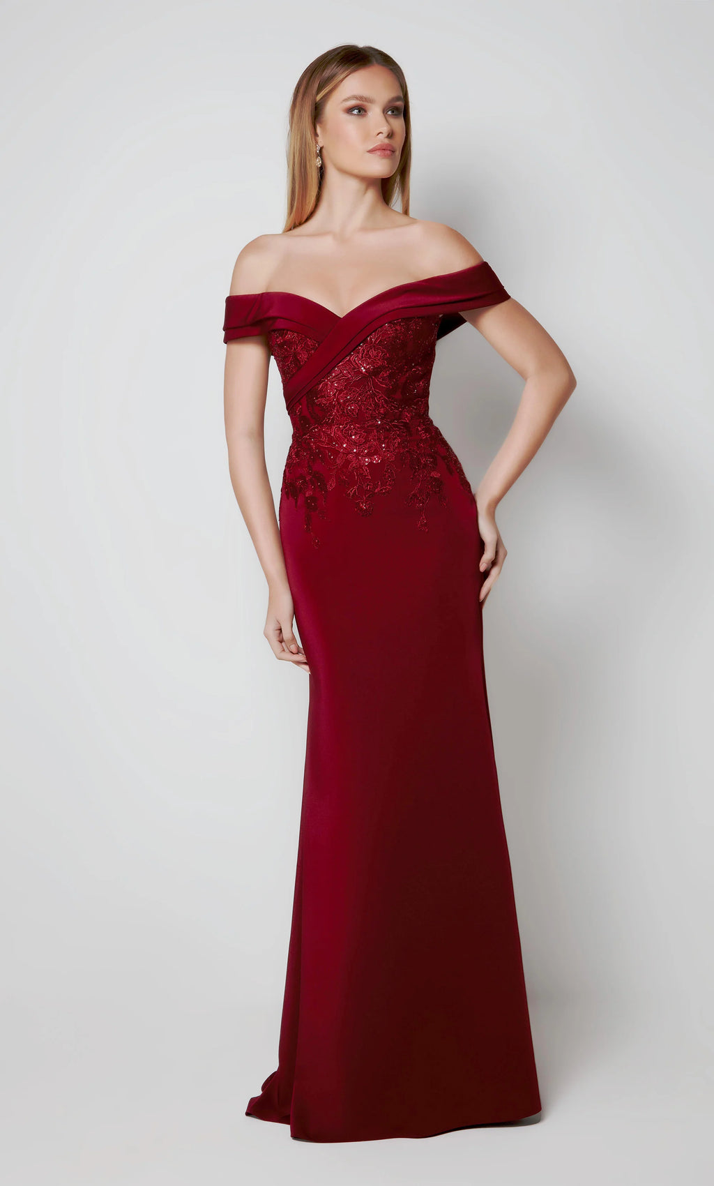 This Alyce Paris Jean De Lys 27571 evening dress features a beaded embroidered bodice with a pleated off-the-shoulder neckline and zipped-up back. This slim-flare formal gown is fashioned in stretch crepe and finishes in a sweep train.