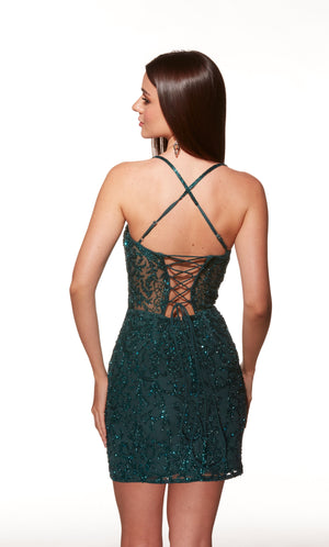 Woman wearing a green sequin dress with a lace-up back on a white background