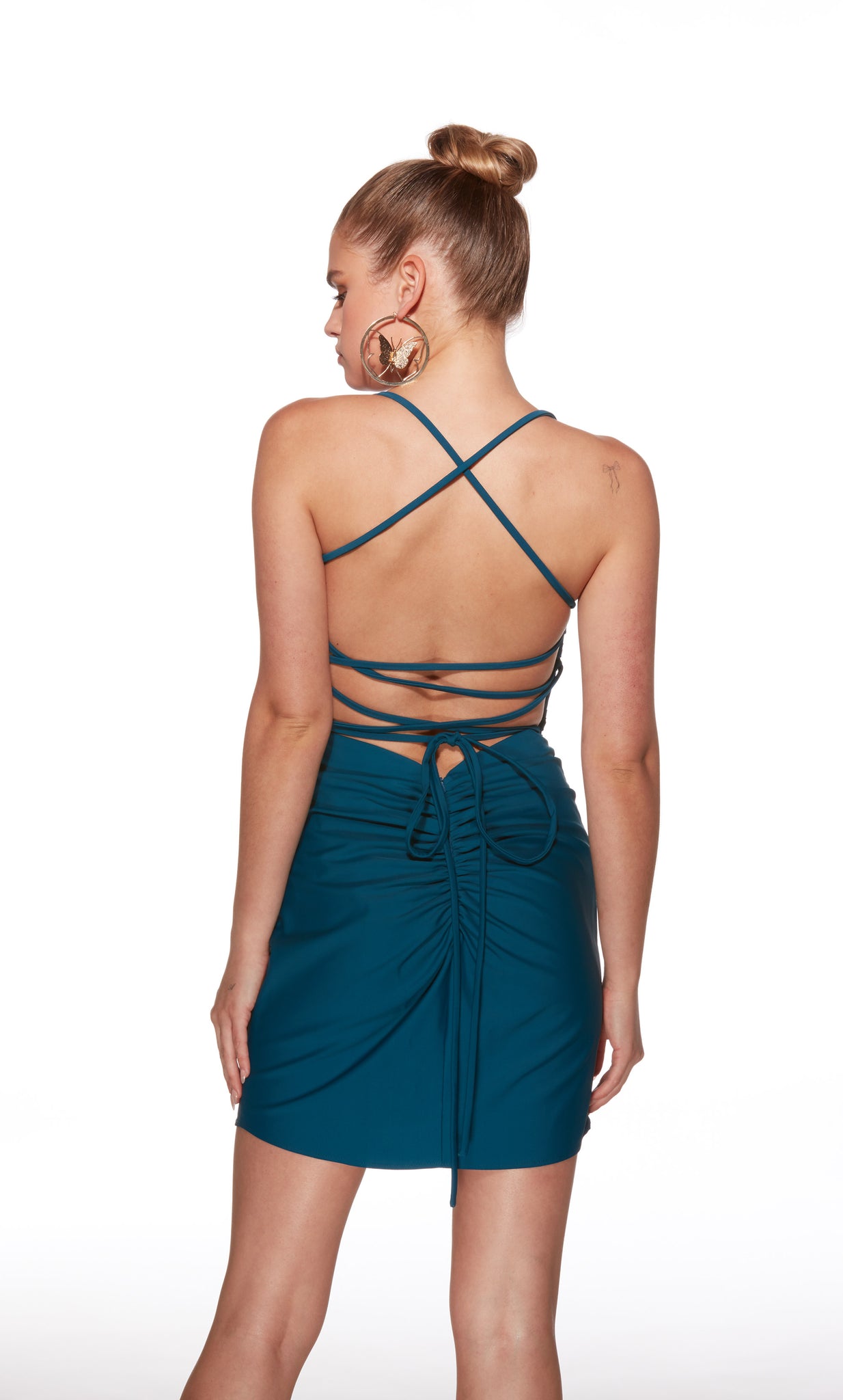 Woman wearing a teal dress with criss-cross straps on a white background