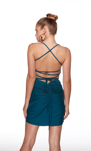 Woman wearing a teal dress with criss-cross straps on a white background