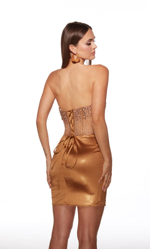 Woman wearing a gold strapless dress with lace-up back on a white background