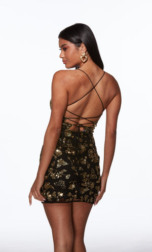 Woman wearing a black and gold sequin dress with criss-cross straps on a white background