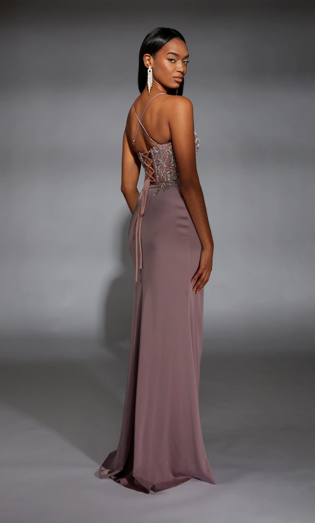 Feel sophisticated in this elegant long dress by Alyce Paris, style 61741. Showcasing a fitted silhouette with a modest v neckline that has delicate satin straps that lead to sa corset lace up back. The corset bodice is fully adorned with glistening beadwork and lace detail. A chiffon skirt has a thigh high slit.