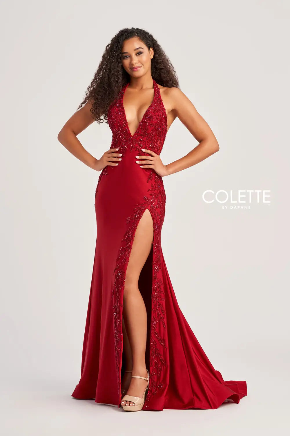 Look sizzling hot at prom in this haute Colette fitted dress style CL5206 made in curve hugging stretch jersey material adorned with beaded lace appliques sequins and sparkling heat set stones. This phenomenal style features a halter strap bodice with deep V neckline and low back with a zipper closure and cut out. The long slim skirt has a sexy high front side slit and sweep train.