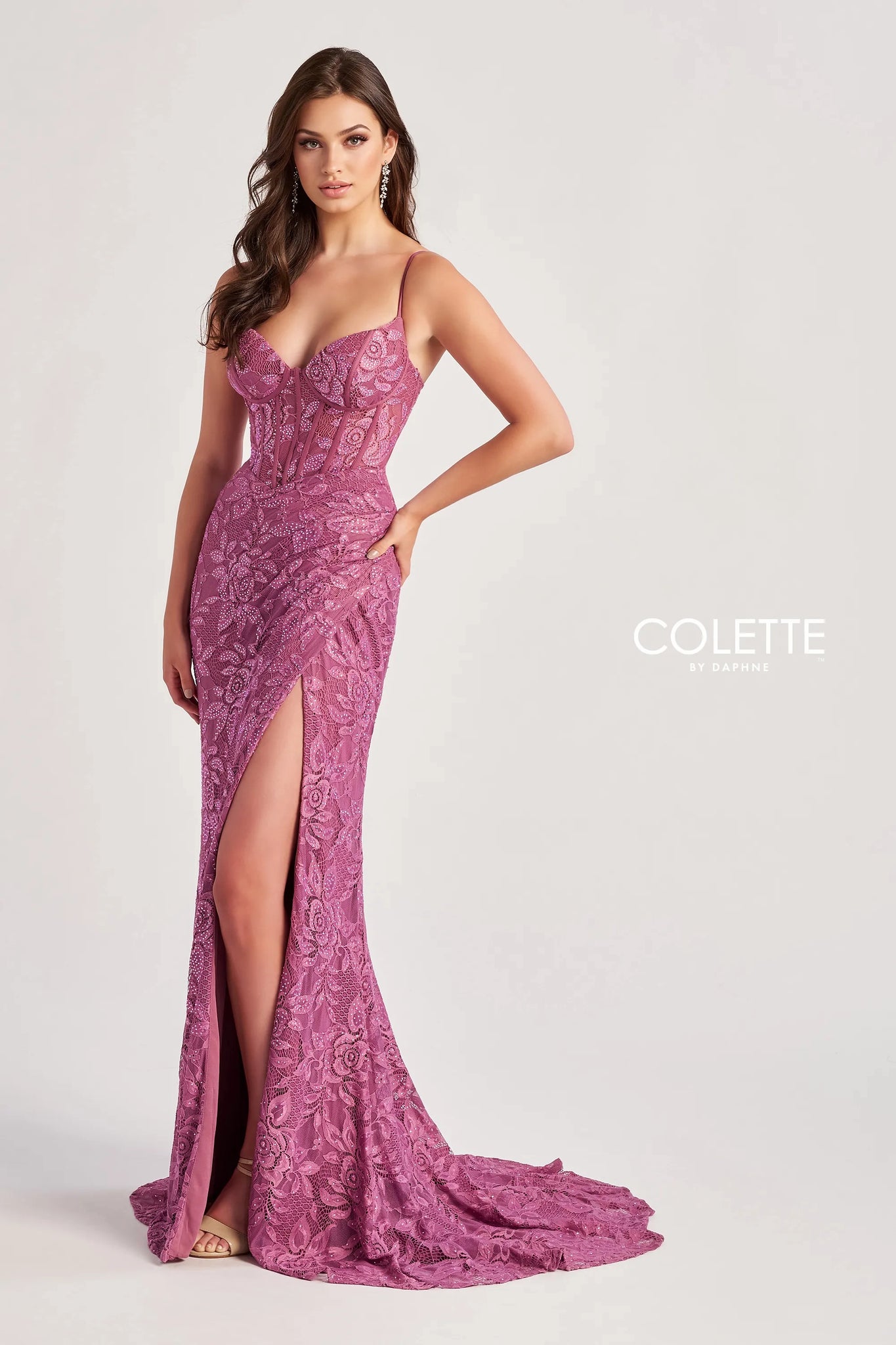 Make heads turn when wearing this long lace fitted dress by Colette, style CL8405. This ensemble has a modern v- neckline with delicate thin straps leading to a unique sexy open corset lace up back that will hug your body beautifully ending with a back zipper back. Showcasing a beautiful silhouette that will hug your body gorgeously at all times. The bottom of this dress has a classy slit and a simple train. Adorned with glistening beadwork and unique floral novelty material.