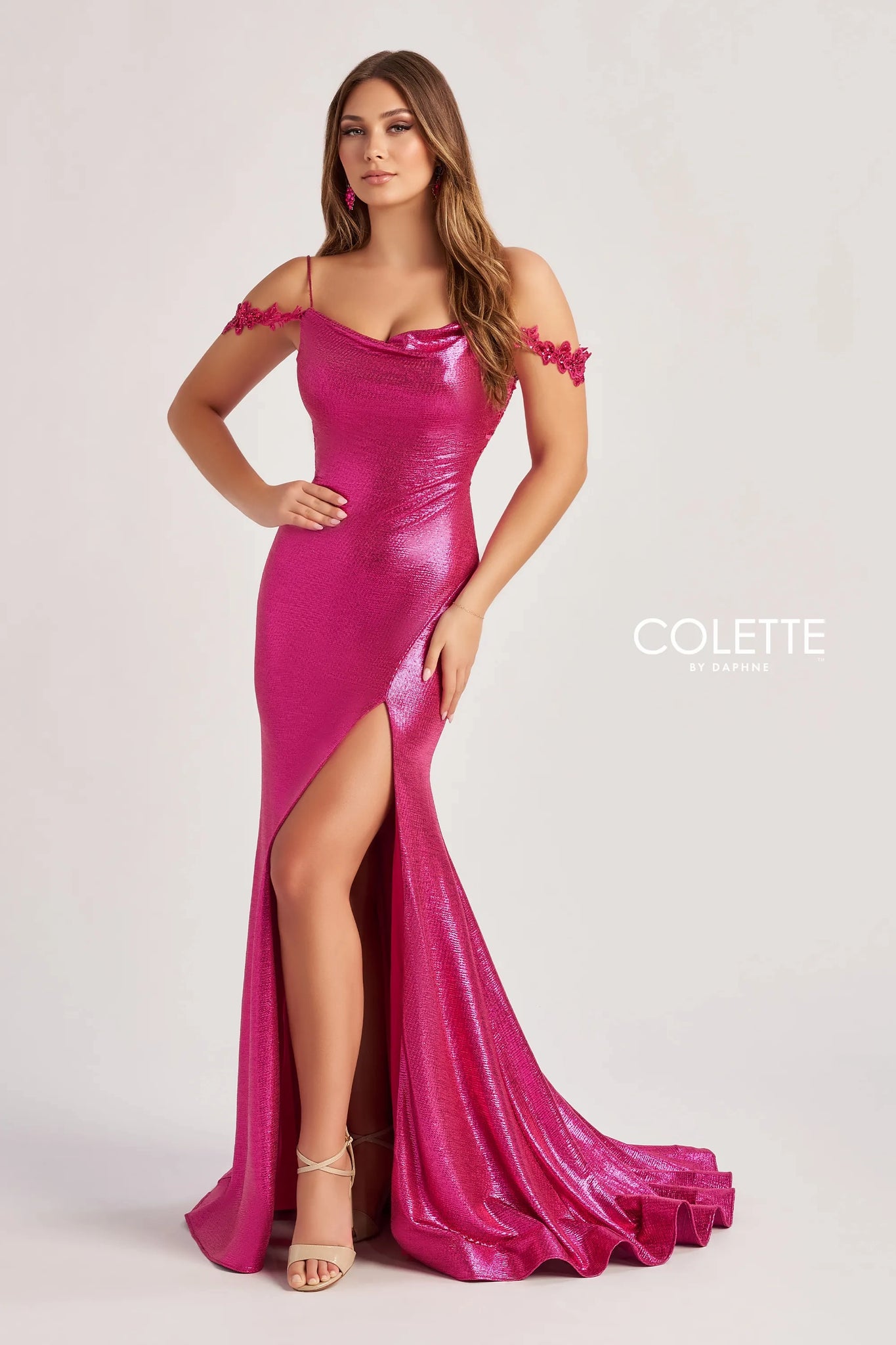 Look both classy and extravagant in this long and fitted dress made by Colette, style CL8565. This dress comes in two different colors which include a bold black and a fuchsia/hot pink. This dress is also off the shoulder with its cap sleeves that have lovely floral detailing. This dress has a perfect slit on the side and a long beautiful train that will have heads turning your way.