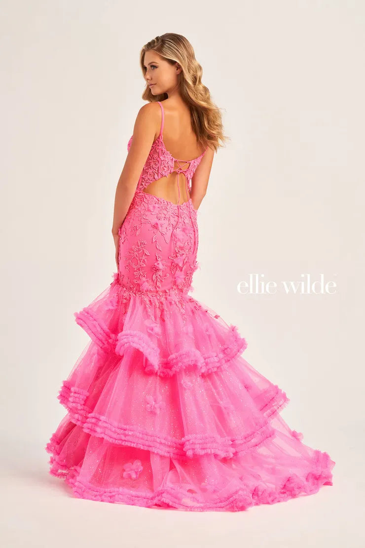 Make a bold fashion statement at your senior prom in this one of a kind Ellie Wilde gown EW35050. Featuring an eye catching low cut neckline with an open illusion back. A unique silhouette features a pleated ruffles and a sexy thigh high slit. Completing the look with a glitter embroidery for the perfect amount of glam.