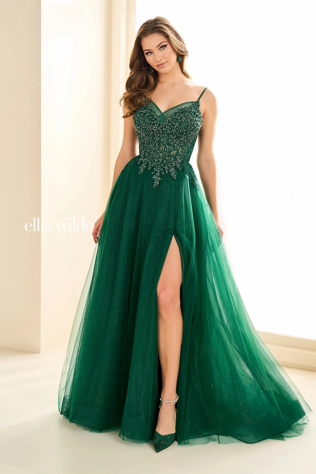Fun and fabulous, this exquisite Ellie Wilde gown EW35059 is an ideal choice for your senior prom. Amp the drama in this ravishing a line silhouette that features a low v neckline. Lavish lace appliques adorn the fitted bodice giving this dress a romantic edge. Made in a fun tulle fabric, glamorous multi layer ruffles give this ensemble a eccentric edge, while the playful side pockets and high slit add a charming touch.