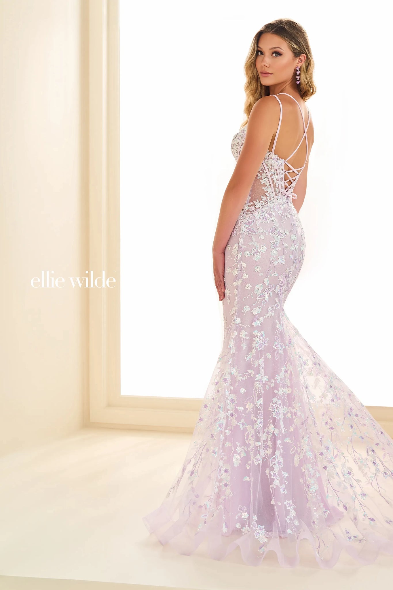 Stand out at your special event wearing Ellie Wilde EW36080 for your special event. This show stopping fitted silhouette showcases a modest v neckline with simple straps leading into a lace up open back for a perfect fit. Shine a;l night long with the all over unique lace embroidery and glitter tulle.