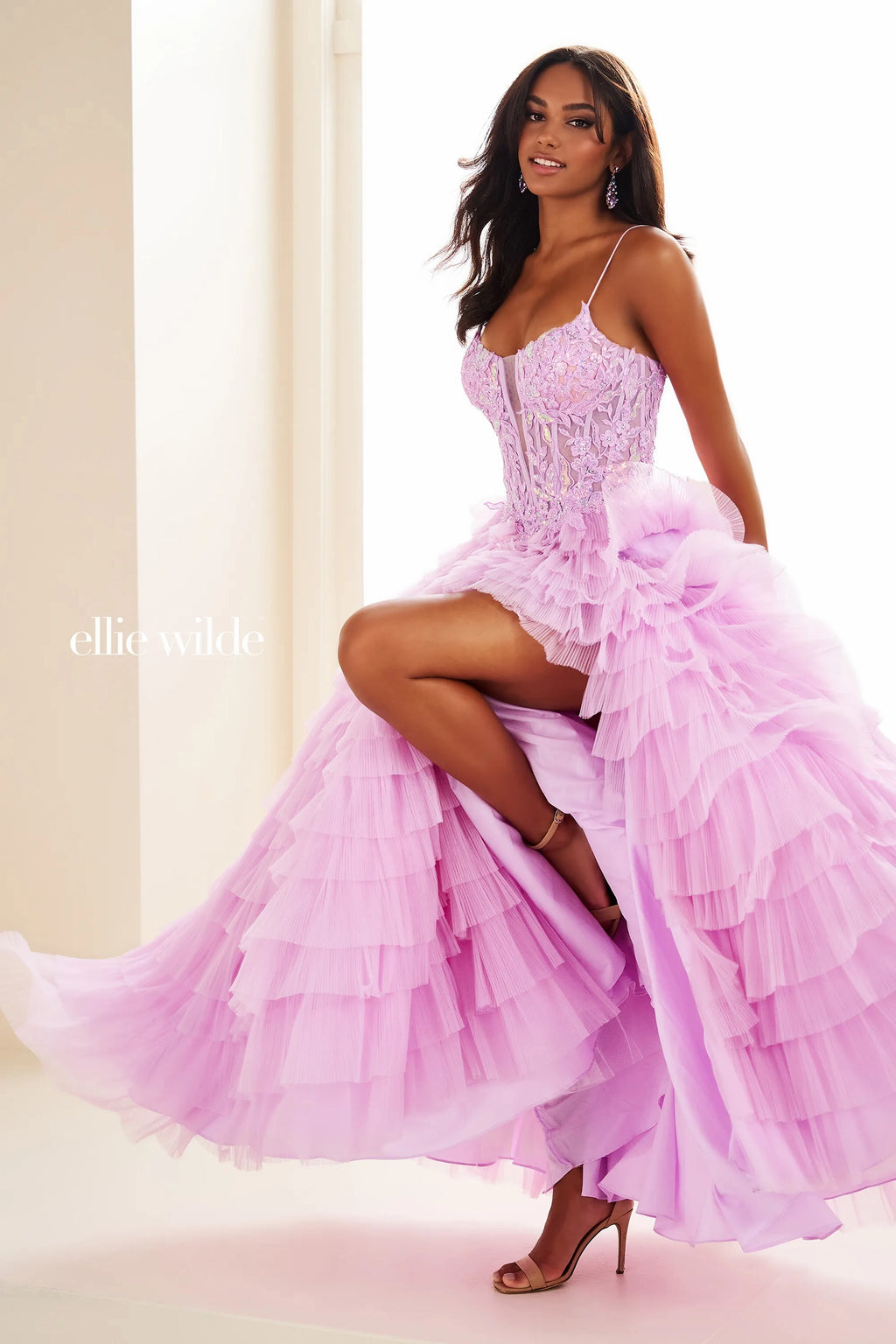 Walk into your special event and strike a pose wearing Ellie Wild style EW36086. This captivating a line silhouette showcases a scoop neckline paired with simple straps for support. Flowing from the fitted laced bodice, a voluminous ruffled skirt gives a dramatic effect showing off your thigh high slit.