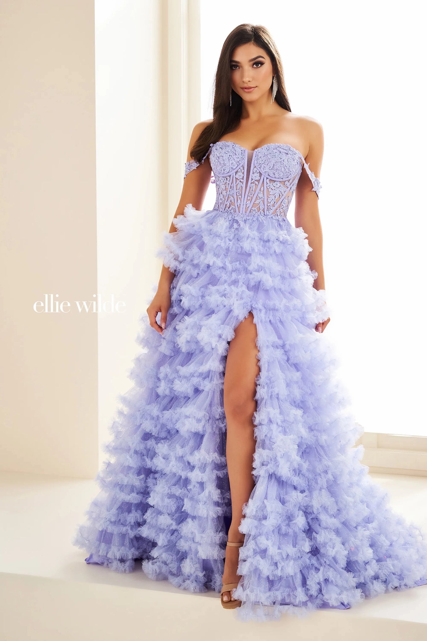 Show off your inner fashionista in this gorgeous A line dress from Ellie Wilde style EW36201. The corset structured bodice is made of sheer illusion with flower appliques adoring it. The ruffled layered aline skirt has a front thigh high side lit and a sweeping train. Included our separate straps to add to the strapless look.