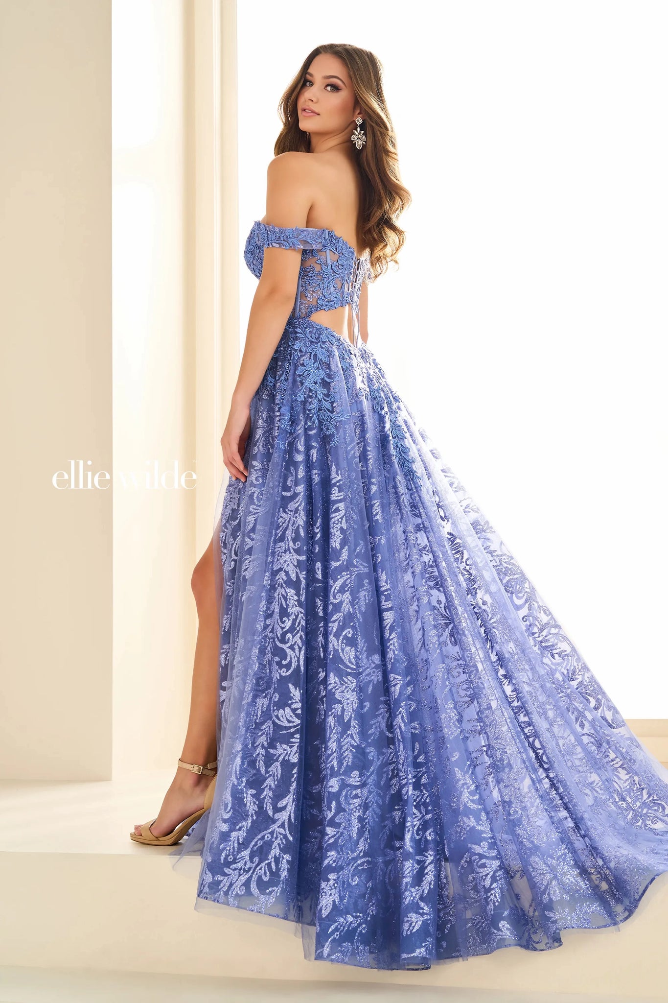 Feel dramatic and glamorous like you just stepped off the red carpet in this gorgeous Ellie Wilde a line dress style EW36209. The off the shoulder bodice neckline is bedazzled with gorgeous appliques. The novelty tulle a line skirt makes it stand out from the rest with a thigh high front side slit and long flowing train.