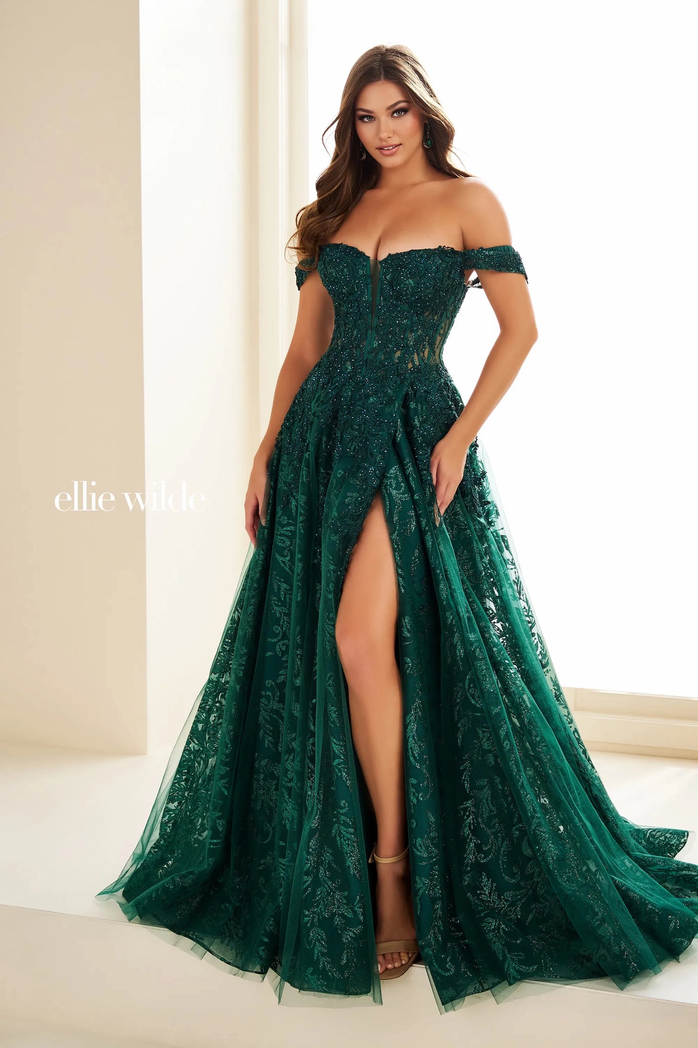 Feel dramatic and glamorous like you just stepped off the red carpet in this gorgeous Ellie Wilde a line dress style EW36209. The off the shoulder bodice neckline is bedazzled with gorgeous appliques. The novelty tulle a line skirt makes it stand out from the rest with a thigh high front side slit and long flowing train.