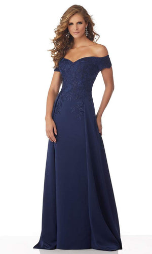 This stretch crepe evening gown presents in an off-shoulder neckline with a form-fitting bodice ornate with beaded lace appliques. The skirt runs in full length and is complemented with an overskirt and a train finish. Zip-up the back.  ONLY 1 IN STOCK  DISCONTINUED STYLE