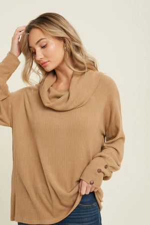Soft rib knit top with a loose draped cowl neck, drooped shoulder, long puff sleeves, and button detail on wrists. 