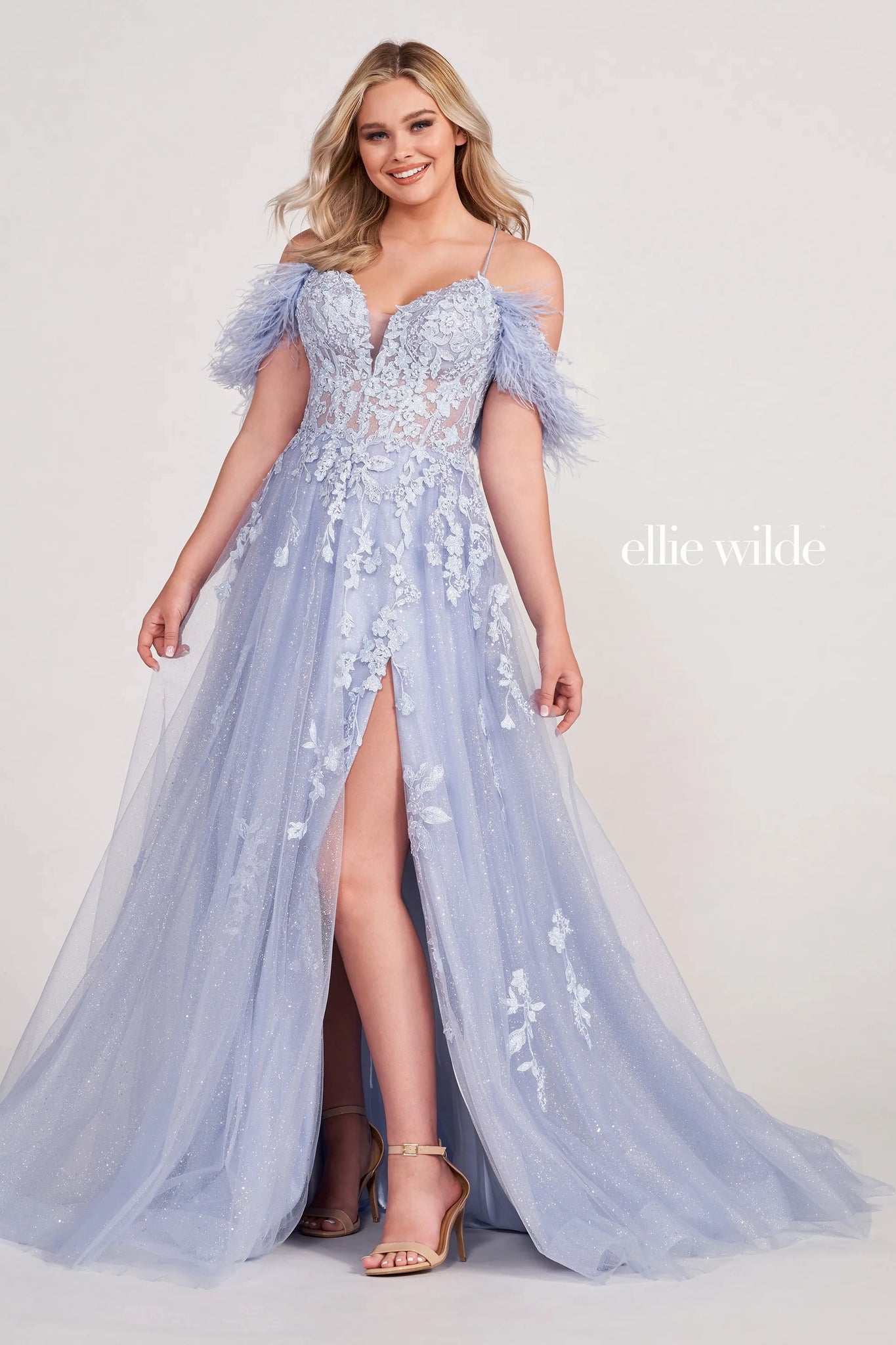 Be your own personal icon in phenomenal long dress EW34066 by Ellie Wilde. This dress grants you options with detachable off the shoulder feathered sleeves that give this dress an elegant touch. The fitted corset bodice features a plunging V neckline along with gorgeous appliques that make a striking transition onto the glittering tulle skirt. The skirt is completed with a thigh high slit and dramatic sweep train that will look stunning in photos.