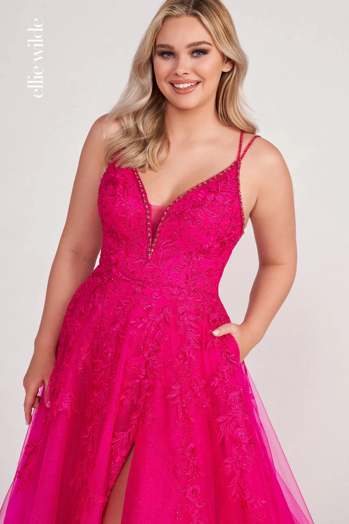 This Ellie Wilde EW34095 petal prom dress is crafted in glitter tulle, with beaded trims on the plunging neckline, double straps, and the strappy open back. Beaded floral embroidery richly embellished this pretty ballgown, finished with in-seam pockets, high slit, horsehair hem, and court train.