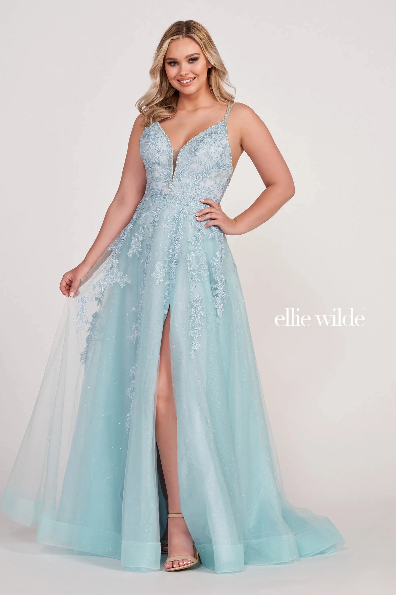 This Ellie Wilde EW34095 petal prom dress is crafted in glitter tulle, with beaded trims on the plunging neckline, double straps, and the strappy open back. Beaded floral embroidery richly embellished this pretty ballgown, finished with in-seam pockets, high slit, horsehair hem, and court train.